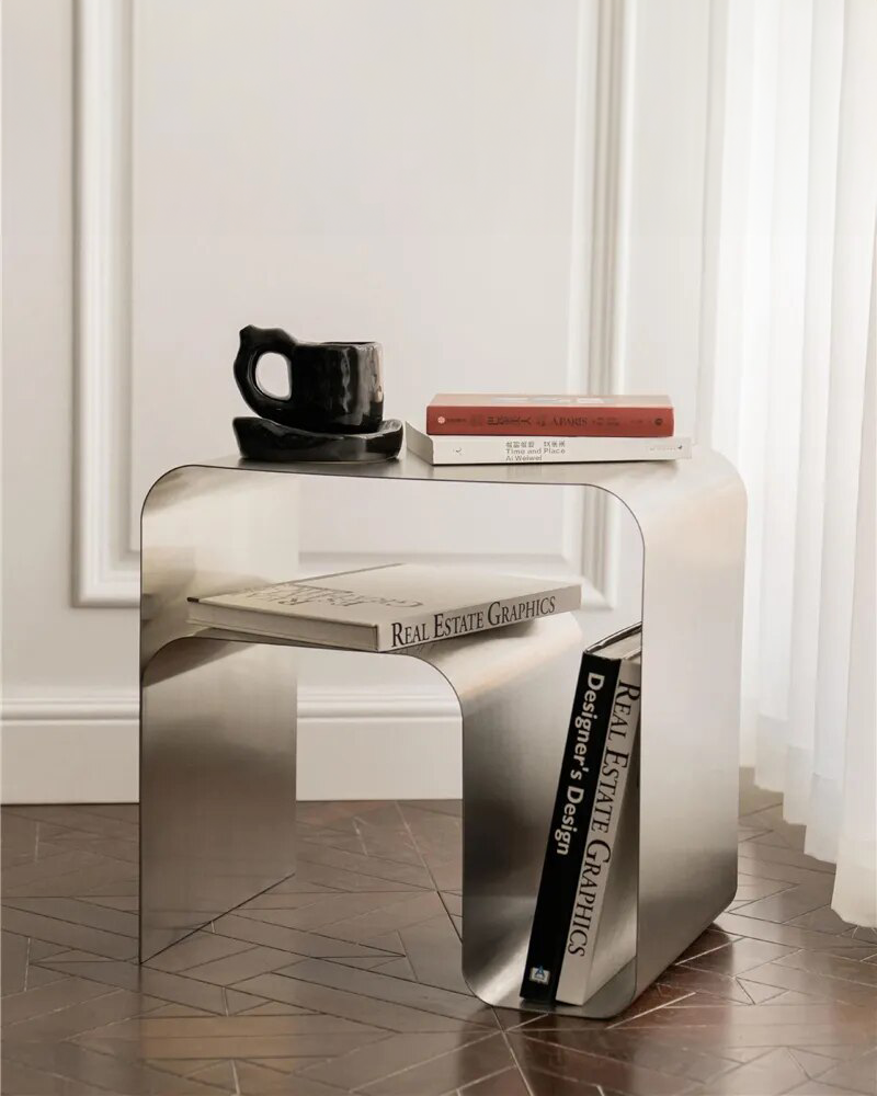 A modern Stainless Steel Side Table with sleek stainless steel construction, combining industrial style and functionality. Features a top surface for displaying items and practical horizontal and vertical storage space inside. Dimensions: W45 x H45 x D35
