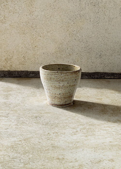 Handmade stone tapered mug, measuring W8cm x H7.5cm. Exhibiting a rugged yet sleek style, this mug is part of a comprehensive set of raw pottery dishes and mugs designed for versatile dining needs.