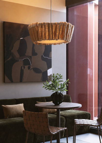Linen Wave linen pendant glowing above a bistro table with woven leather chairs and an olive velvet sofa